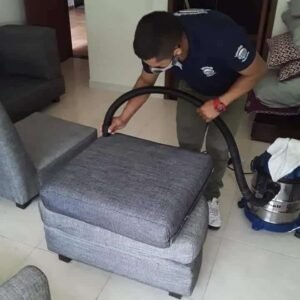 Técnico de Lavandería La Especial aspirando un puff cuadrado sin espaldar completamente limpio como parte del servicio de limpieza de muebles a domicilio en Cali, Colombia.